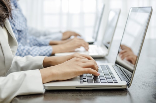 Hands working on computers in a business setting