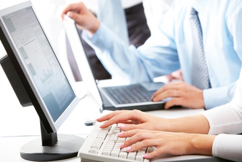 Hands working on computers in a business setting